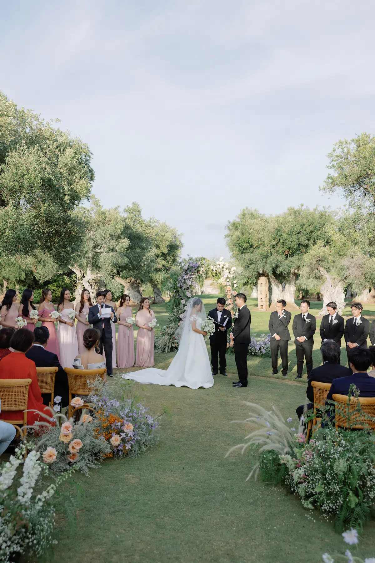 Outdoor Wedding Ceremony Exchanging Vows Under Floral Arch