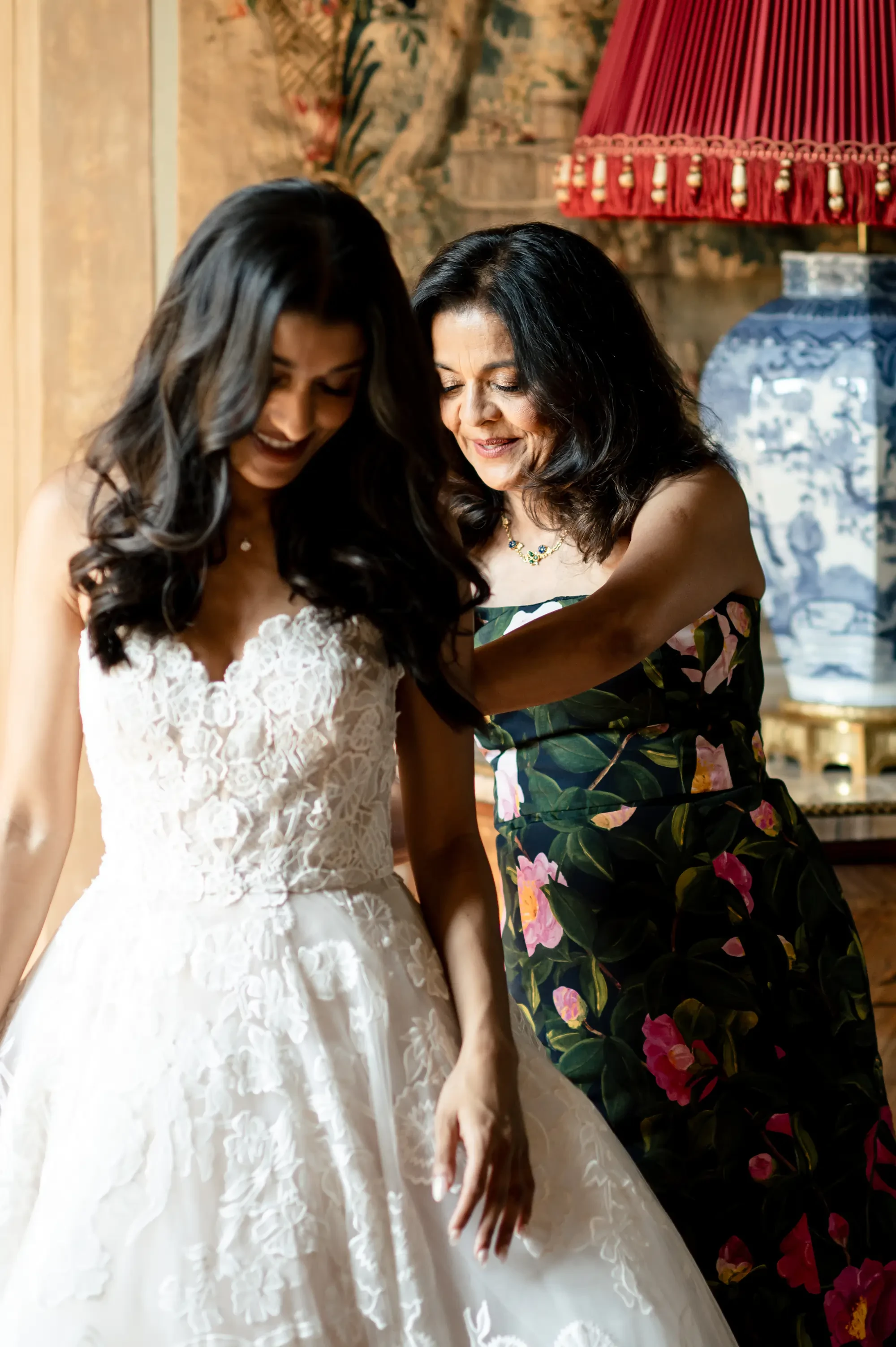 Mother Of The Bride Helping Bride Put On Wedding Dress